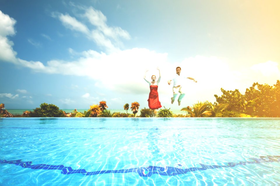 man and woman jumping onto pool