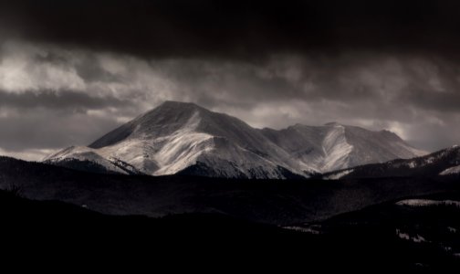 grayscale photography of mountain under cloudy sky photo