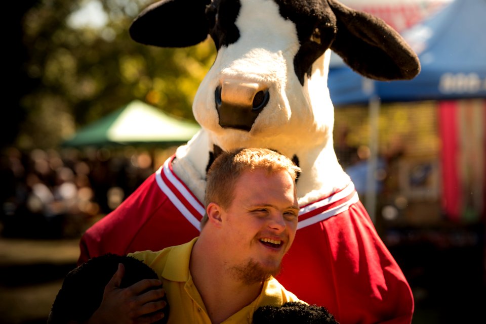 smiling man wearing yellow polo shirt standing near cattle cosplay