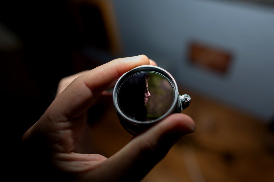 person holding round grey mirror selective focus photography