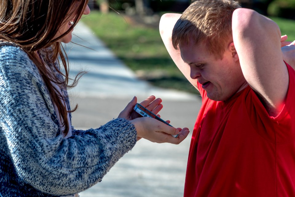 woman holding phone in front of man wearing red shirt