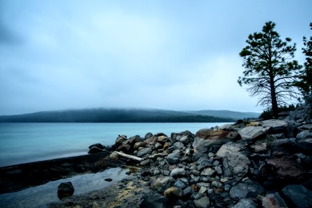 rocks beside body of water under white and gray sky photo