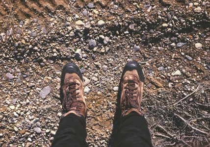 person wearing brown shoes standing on dirt and stone ground photo