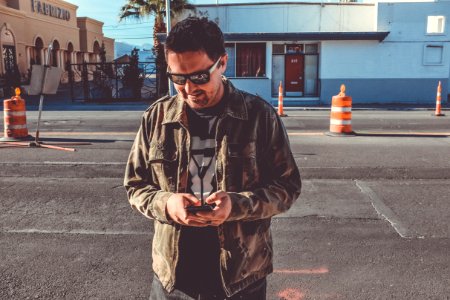 man holding smartphone near road
