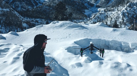 man in black hooded jacket controlling black drone photo