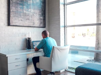 man sitting on armchair using laptop computer photo