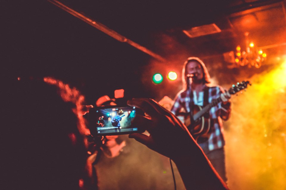 person taking photo of man playing guitar