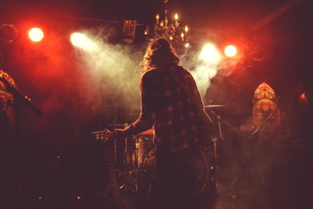 person standing on stage holding guitar close-up photography photo