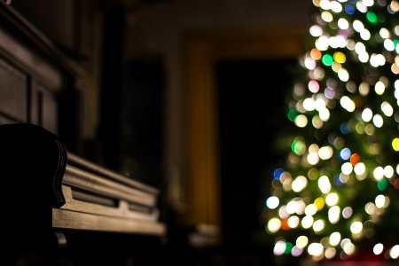 closeup photo of black piano near lighted Christmas tree
