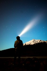 man standing in front of mountain watching light on sky photo