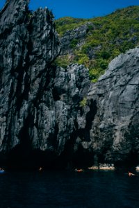 people on sea outside rock cave