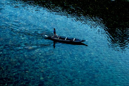 top view photo of man riding wooden boat on calm body of water photo