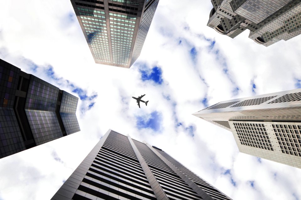 low-angle photo of five buildings with airplane in the middle of picture