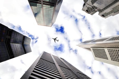 low-angle photo of five buildings with airplane in the middle of picture