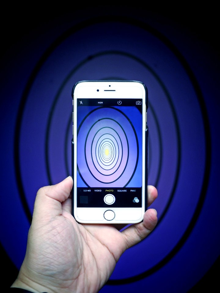 A person taking a picture of blue oval shapes with their phone.