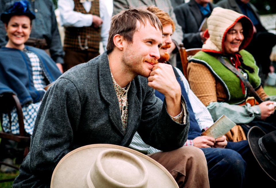 man wearing black coat sitting beside man in blue vest during daytime photo