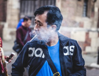 man in black Adidas leather jacket smoking cigarette photo