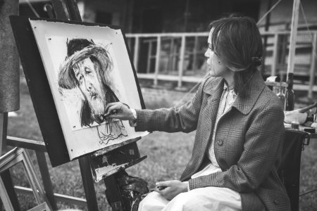 grayscale photography of woman sitting while painting photo