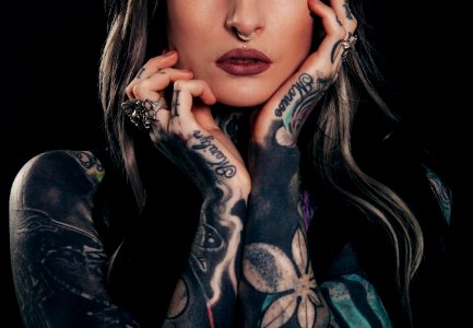 woman showing body tattoo while holding her face photo