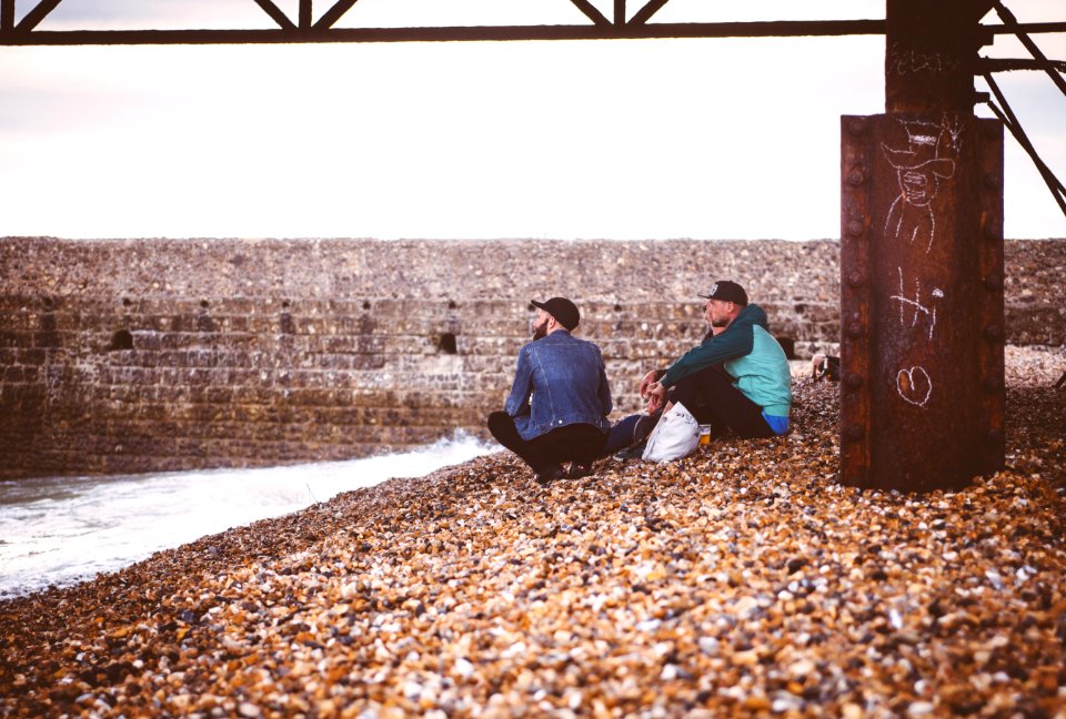 two men sitting near body of water