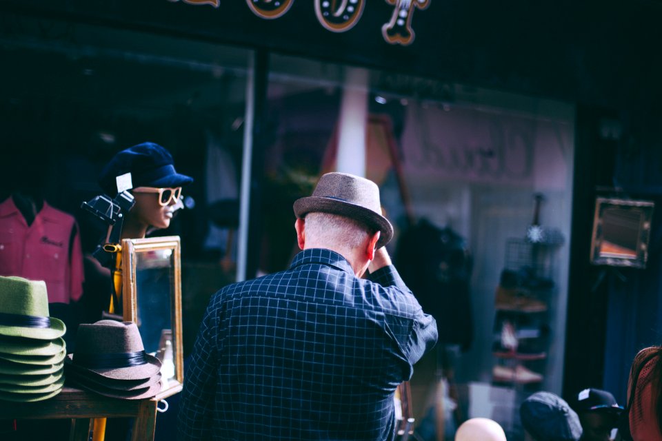 man holding his brown fedora hat facing backwards