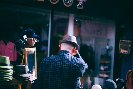man holding his brown fedora hat facing backwards