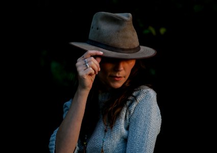 woman in blue sweater holding her hat photo