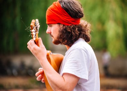 shallow focus photography of man playing guitar outdoors photo