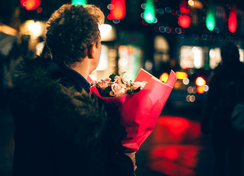 man in black faux fur coat holding bouquet of floweers photo