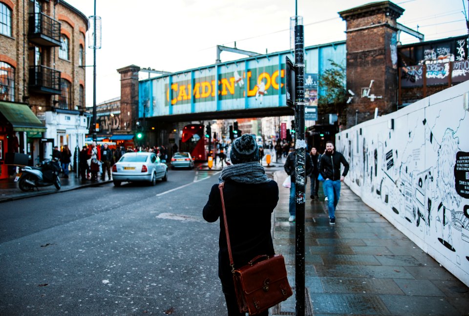 people walking on black concrete road beside buildings under white sky during daytime photo