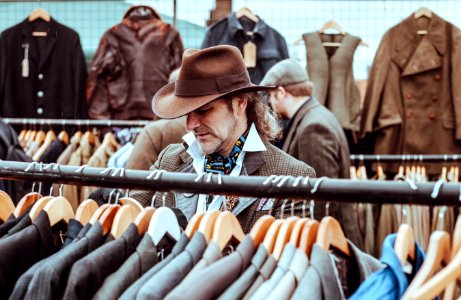 man in brown cowboy hat in front of hanged suit jackets photo