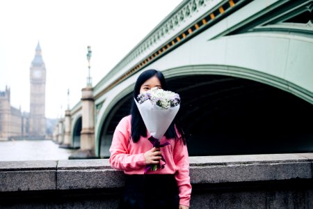woman holding flower bouquet standing beside concrete railings photo
