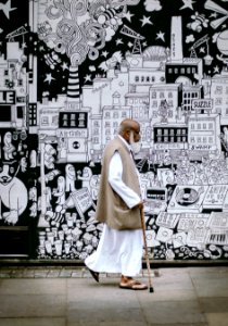 man wearing white sherwani robe beside graffiti photo