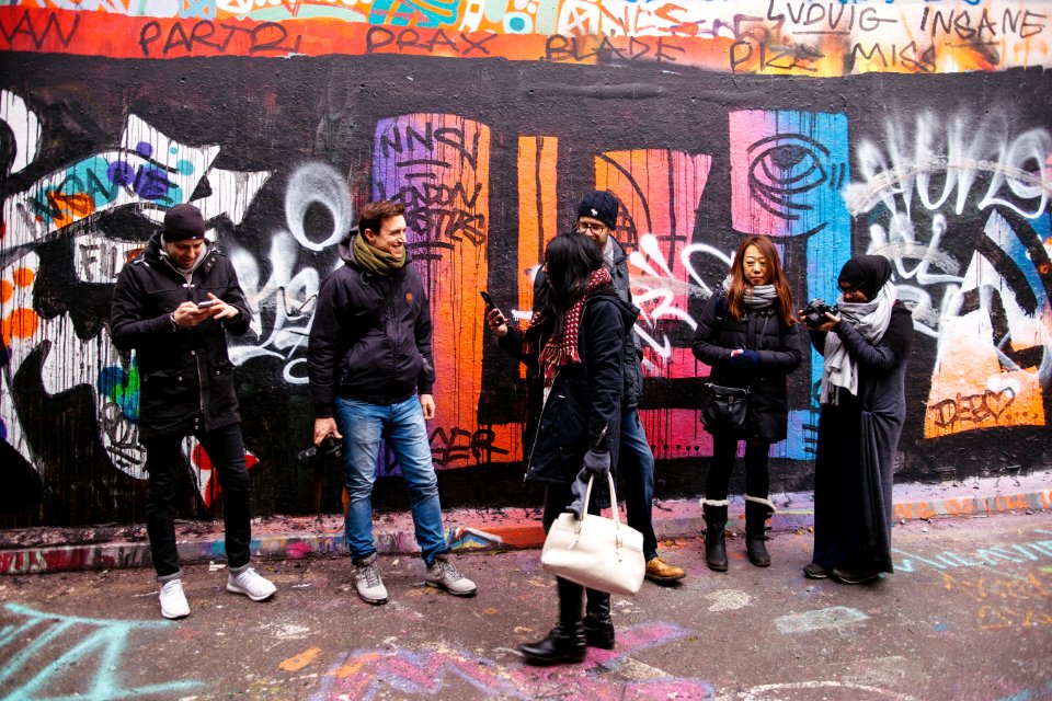 people walking beside painted wall