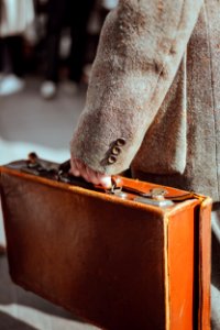 person wearing coat carrying suitcase photo