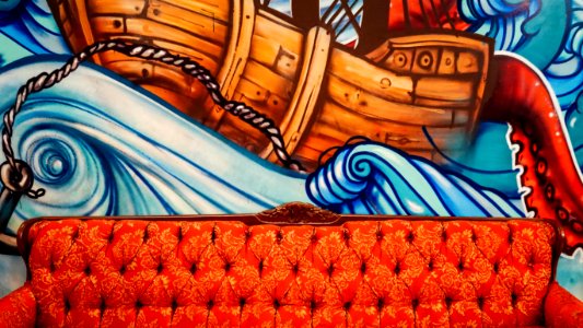 tufted orange sofa with brown boat mural paint in the back