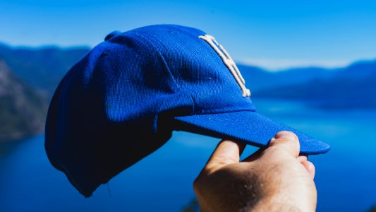 person holding blue fitted cap