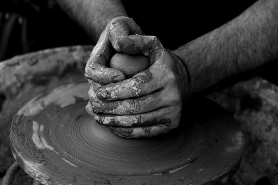 grayscale photography of person's hand making pot