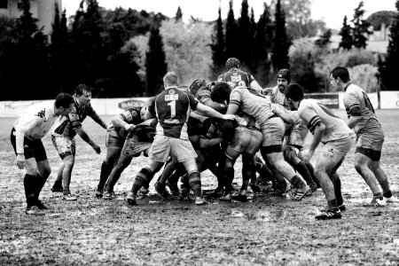 grayscale photography of men playing rugby on muddy land photo