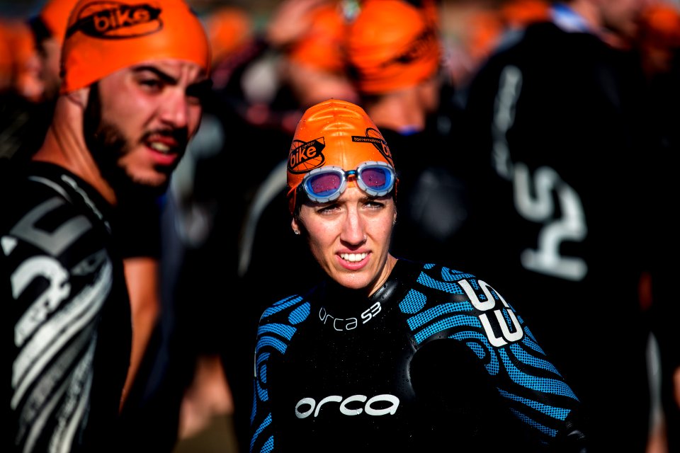 selective focus photography of woman wearing orange head cap and blue rashguard