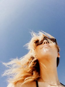 A happy blonde girl wearing glasses outside. photo