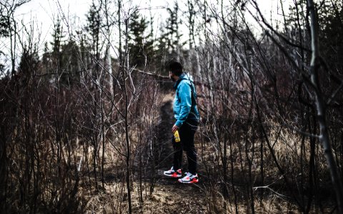 man in blue jacket and black pants in woods photo