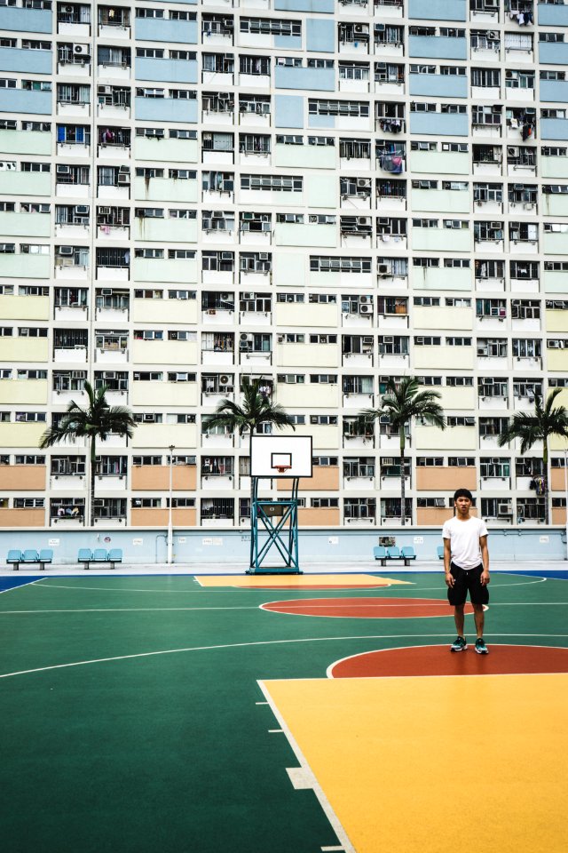 man standing on basketball court near building