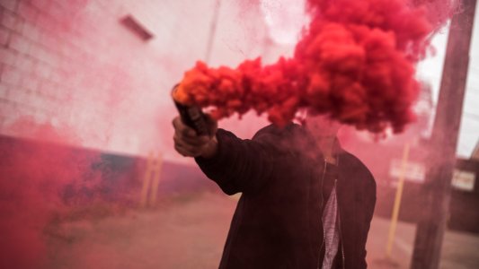 man holding red smoke grenade photo
