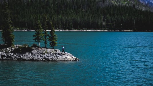 person walking on rock beside body of water photo
