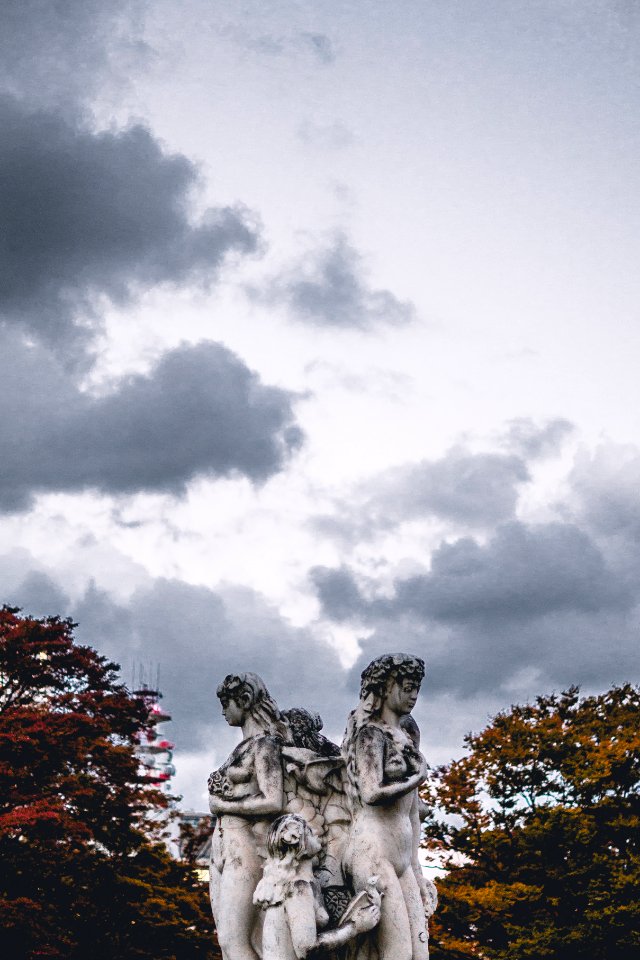 female concrete statue under white clouds