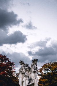 female concrete statue under white clouds