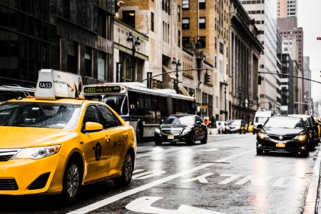 yellow taxi travelling on city streets photo