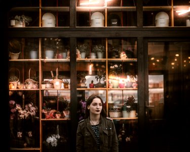 woman in black leather jacket standing beside glass cabinet photo