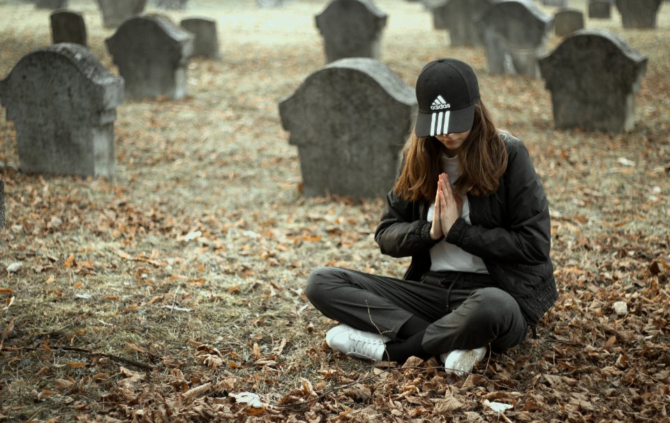 woman in black jacket and black pants sitting on ground with dried leaves photo